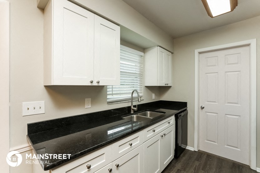 a white kitchen with black counter top and white cabinets