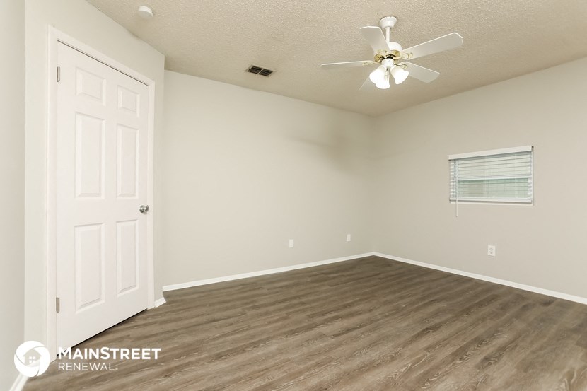 the spacious living room of this manufactured home has a ceiling fan and wood flooring