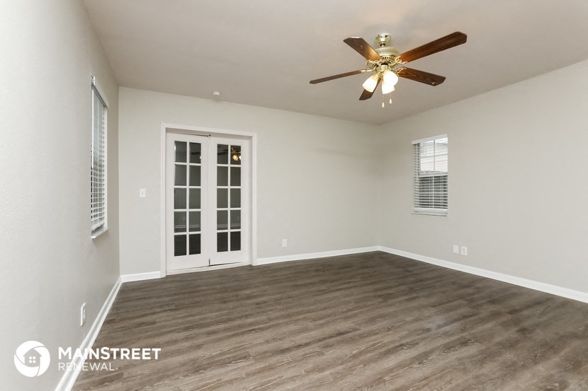 the spacious living room of this manufactured home has a ceiling fan and wood flooring