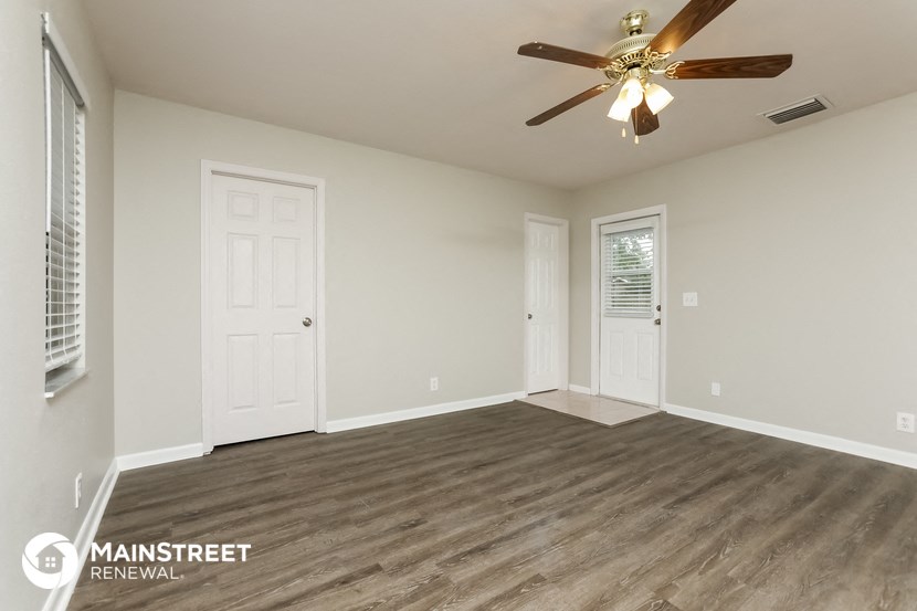 the spacious living room with wood flooring and a ceiling fan