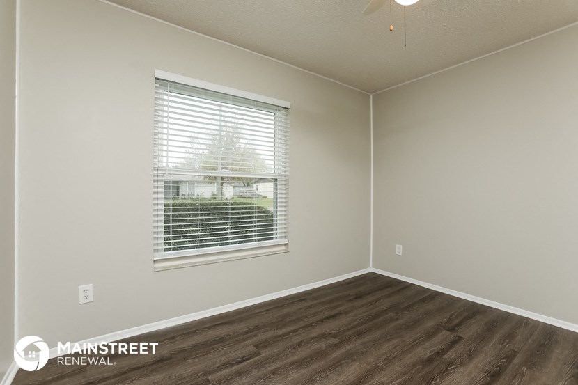 the interior of an empty room with wood floors and a window