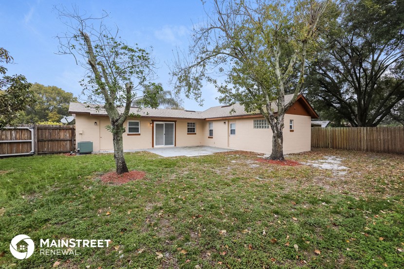 a beige house with two trees in the yard
