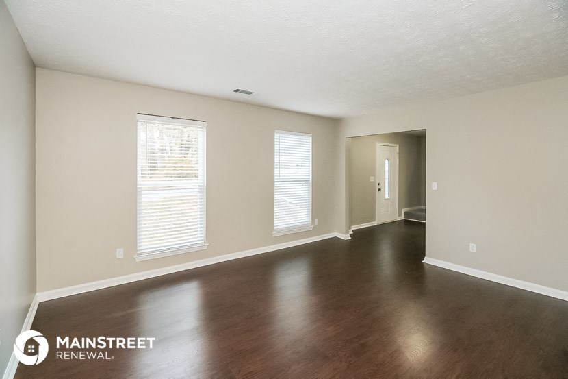 an empty living room with wood floors and white walls