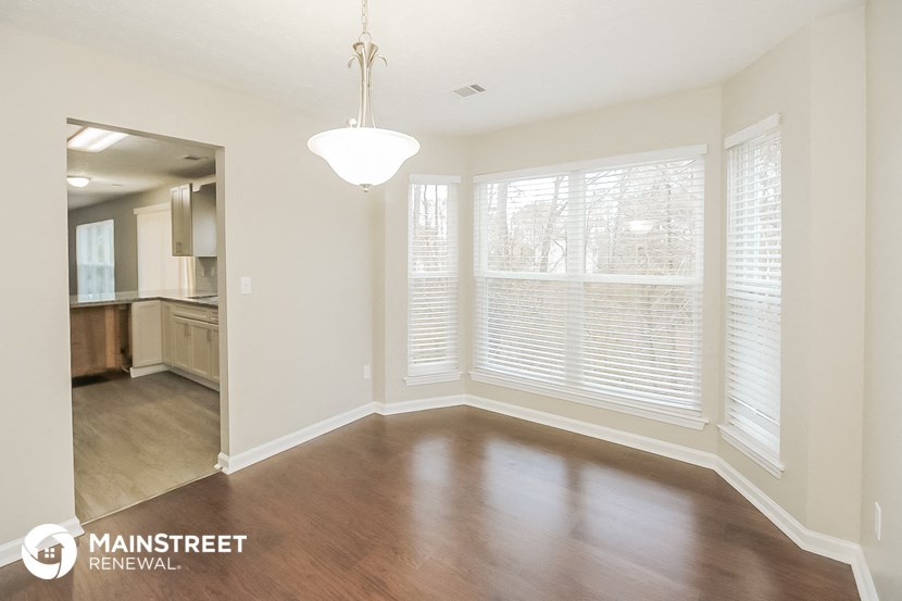 an empty living room with wood floors and a large window