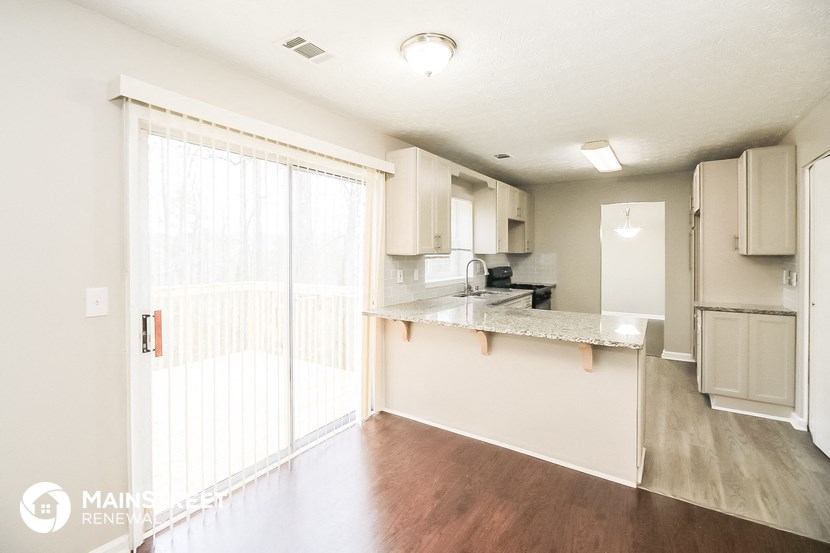 an open kitchen with a sliding glass door to the living room