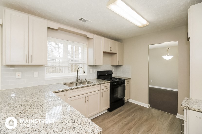 a kitchen with white cabinets and granite counter tops and black appliances
