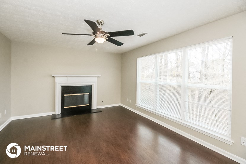 a living room with a fireplace and a ceiling fan