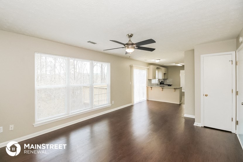 an empty living room with wood floors and a ceiling fan