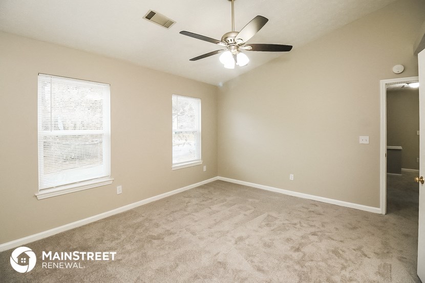 the spacious living room with carpeting and a ceiling fan