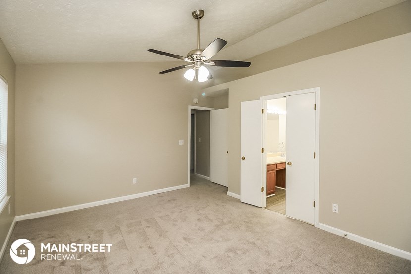 a spacious living room with carpet and a ceiling fan