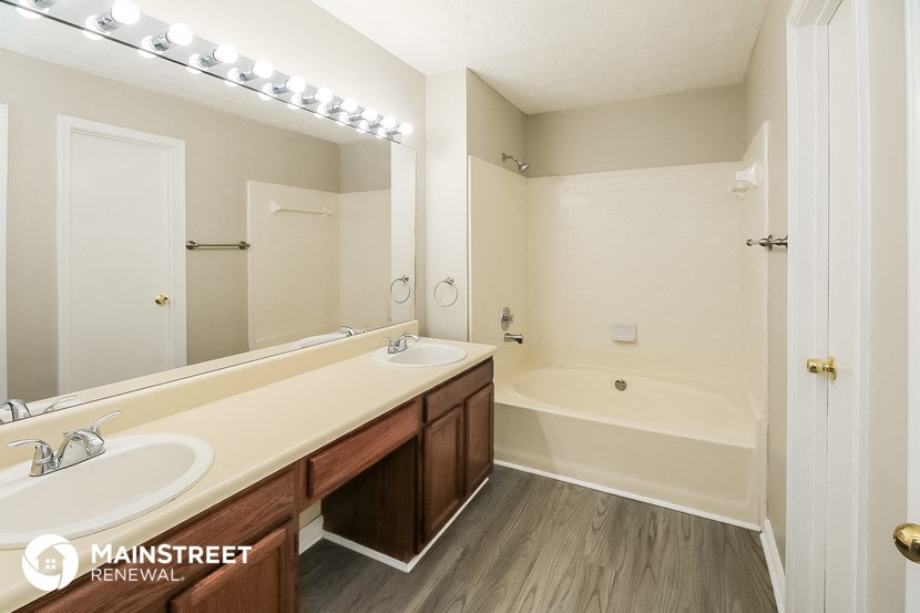 a bathroom with two sinks and a tub and a mirror