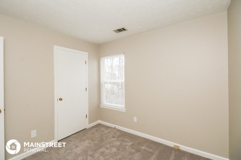 a bedroom with a carpeted floor and a white door