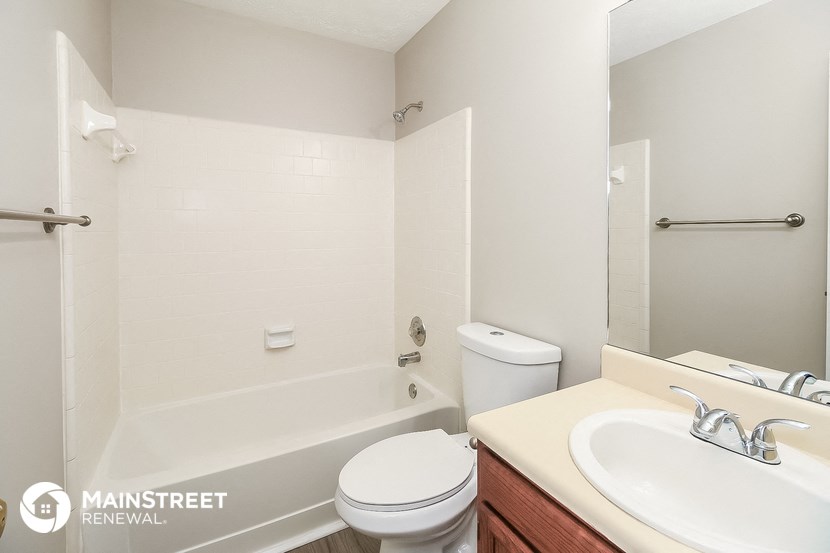 a bathroom with a toilet sink and tub and a mirror