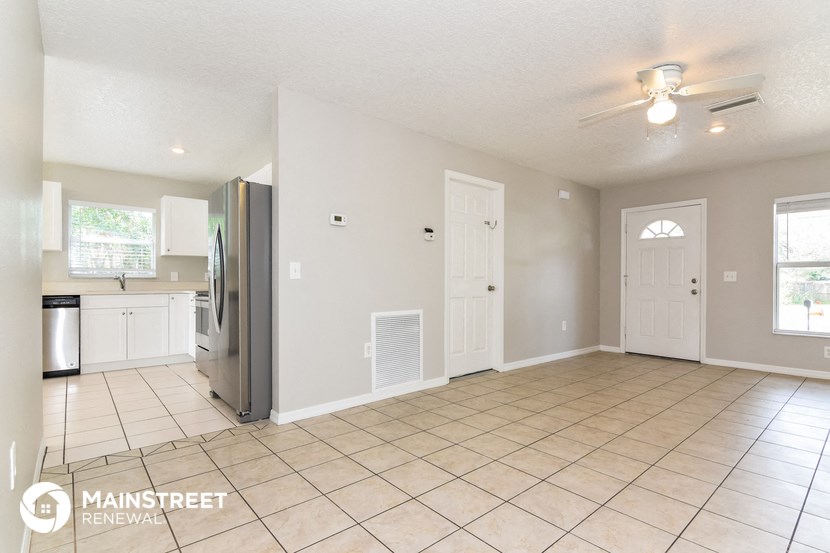an empty kitchen with tile flooring and a stainless steel refrigerator