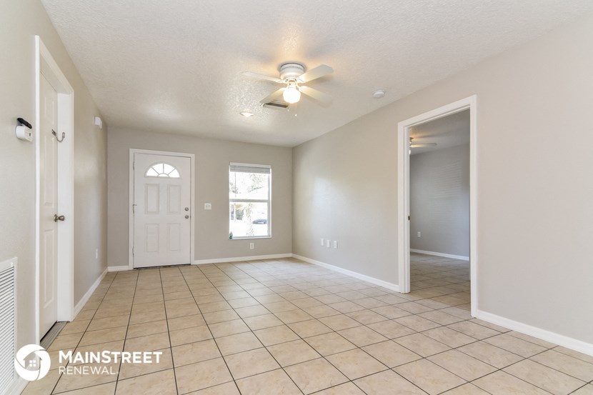 an empty living room with a white door and a ceiling fan