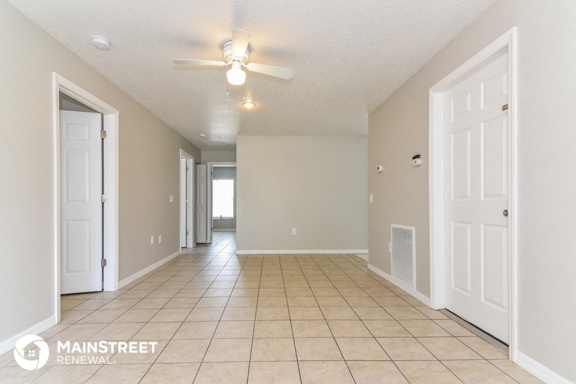 an empty living room with a ceiling fan and a tiled floor