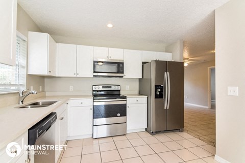 a kitchen with white cabinets and a stainless steel refrigerator