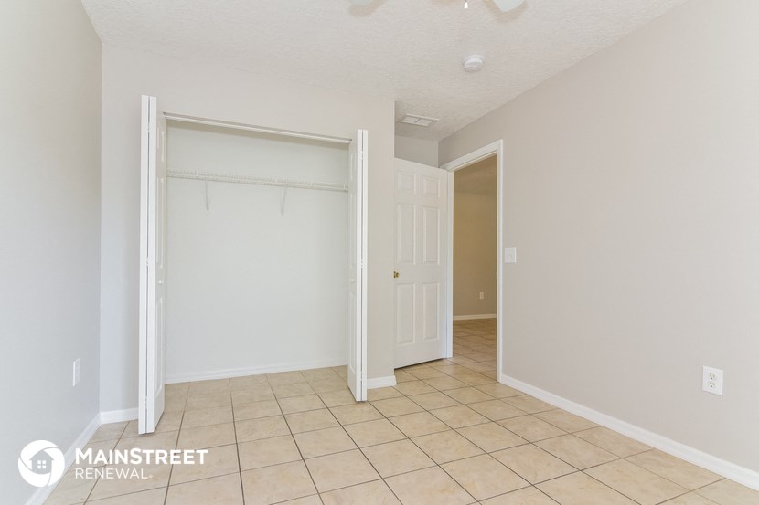 the living room of a home with a tiled floor and a closet