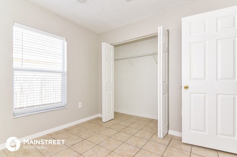 a bedroom with a closet and a window and a tiled floor