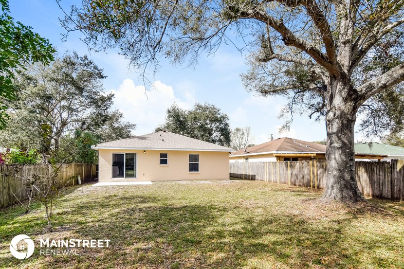 a small yellow house with a yard and a tree
