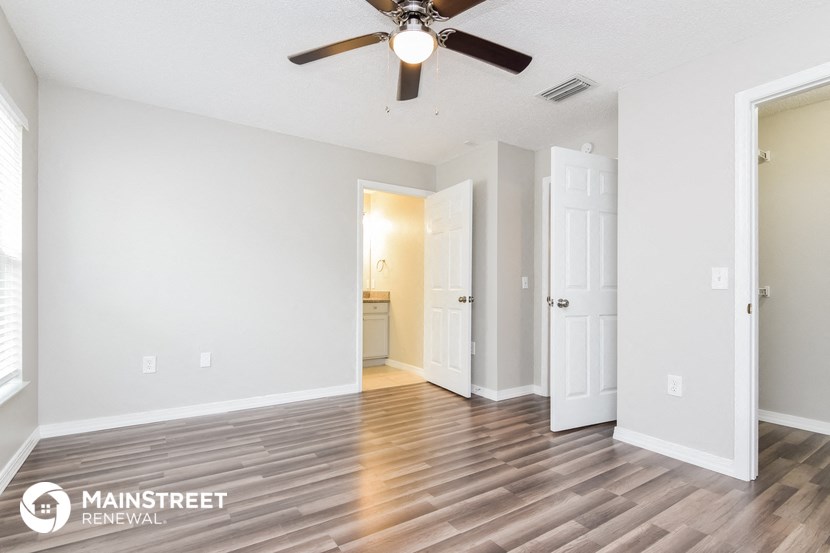 the spacious living room with wood flooring and a ceiling fan