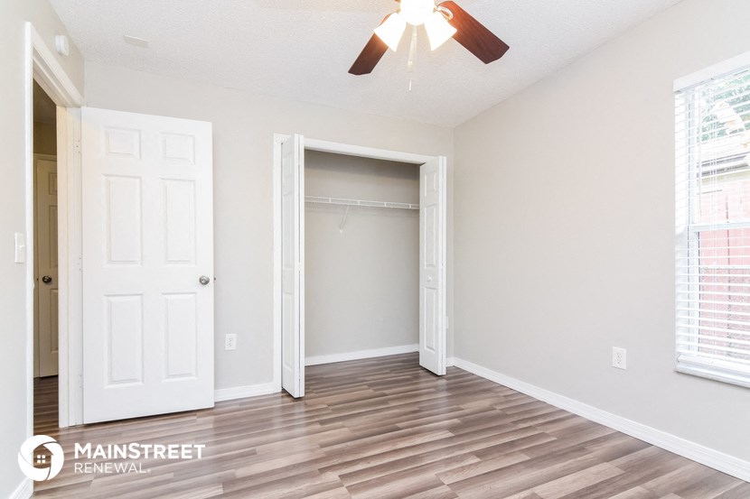 the spacious living room with a closet and a ceiling fan