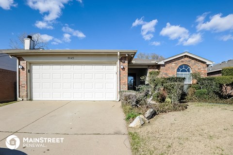 a white garage door in front of a brick house