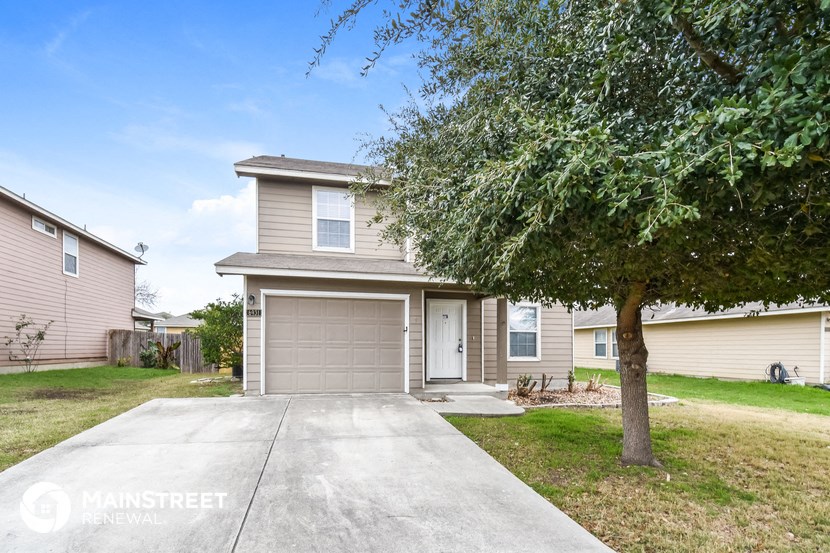 a beige house with a garage door and a tree