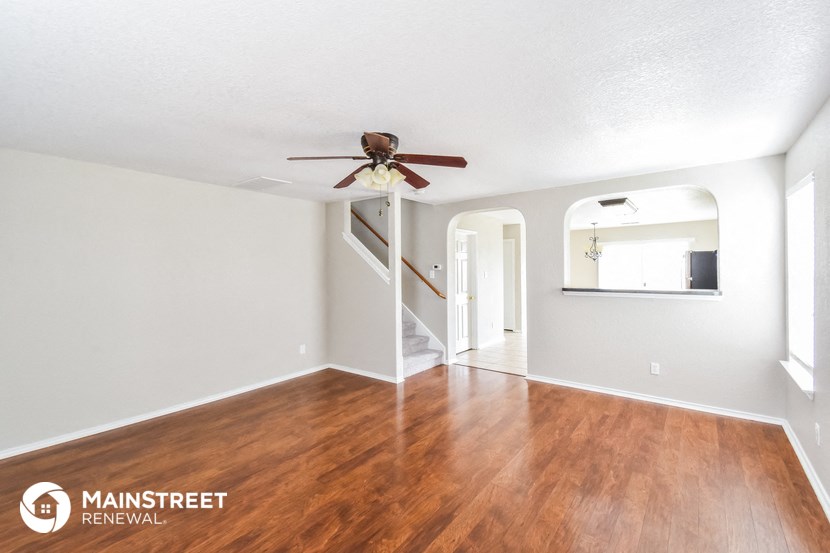 a living room with wood floors and a ceiling fan