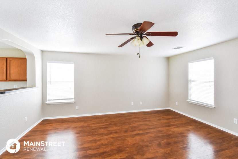 an empty living room with a ceiling fan and wood floors