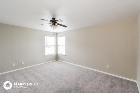 the spacious living room with ceiling fan and carpet