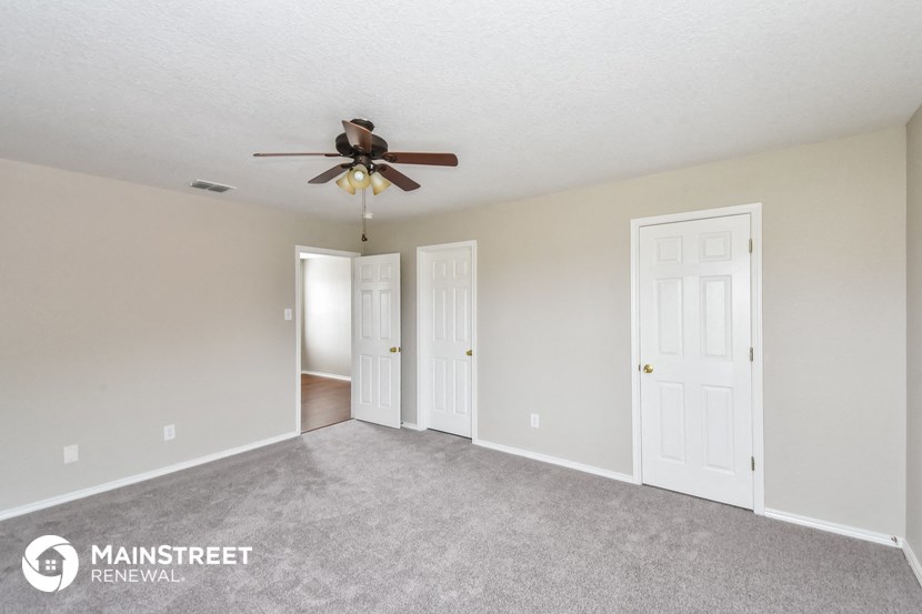 an empty living room with a ceiling fan and white doors