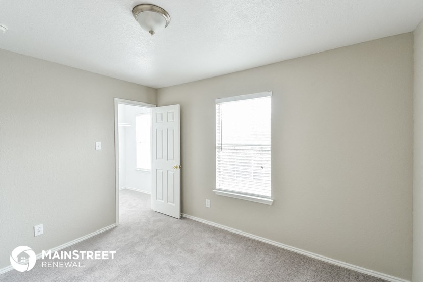 the living room of an apartment with a white door and window