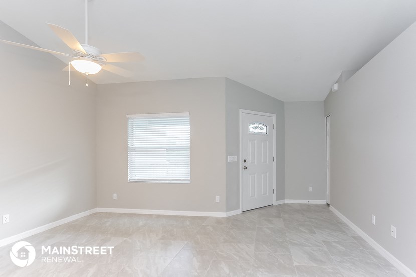 the living room of an empty home with a ceiling fan