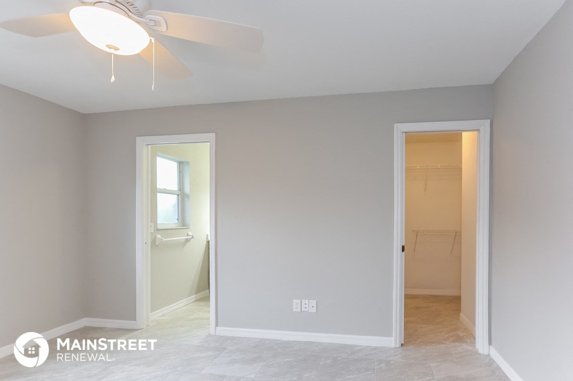 an empty room with a ceiling fan and a door to a bathroom