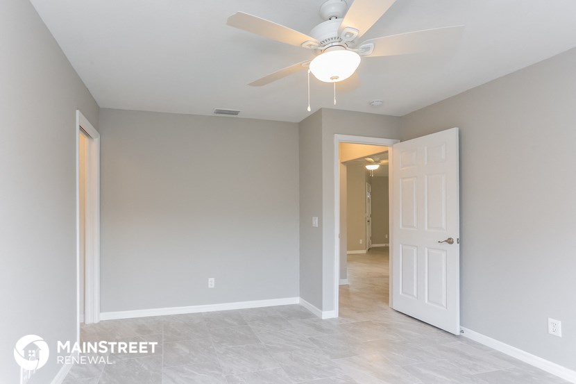 the master bedroom has a ceiling fan and tile flooring