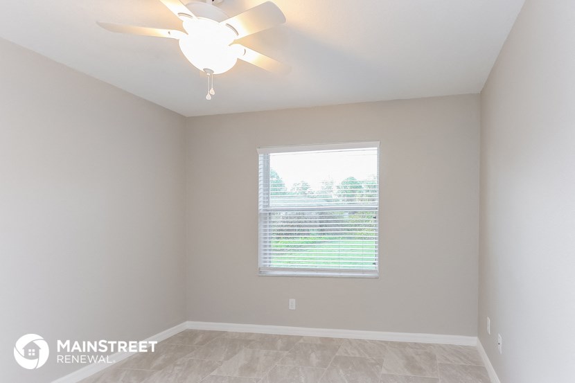 the master bedroom has a large window and a ceiling fan