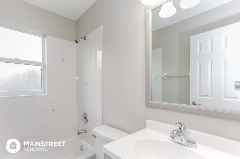 a white bathroom with a sink and a mirror and a tub