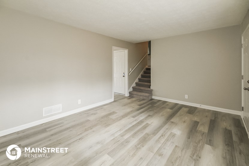 the living room of an apartment with wooden floors and a staircase