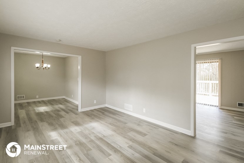the living room and dining room of an empty house with wood flooring