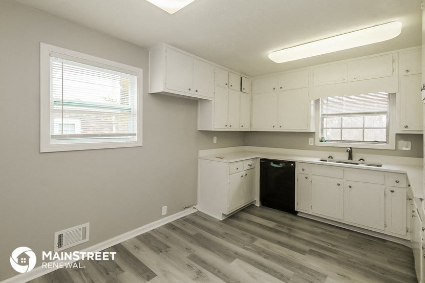the kitchen of an apartment with white cabinets and a black dishwasher