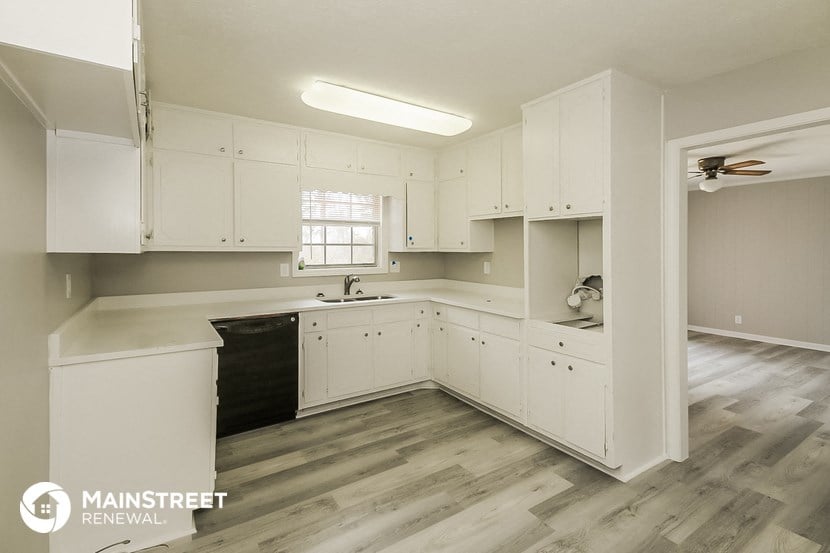 a white kitchen with white cabinets and a black sink