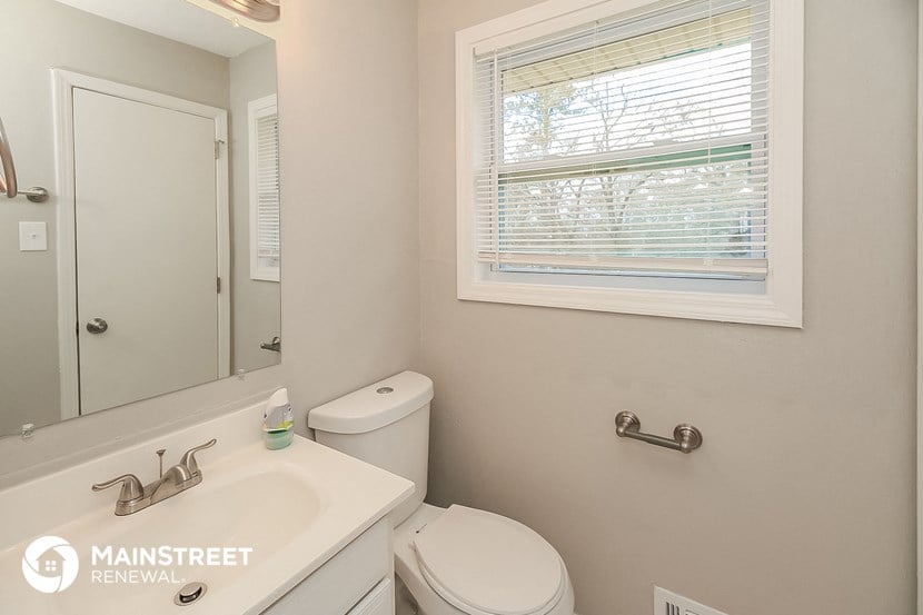 a bathroom with a toilet and a sink and a window