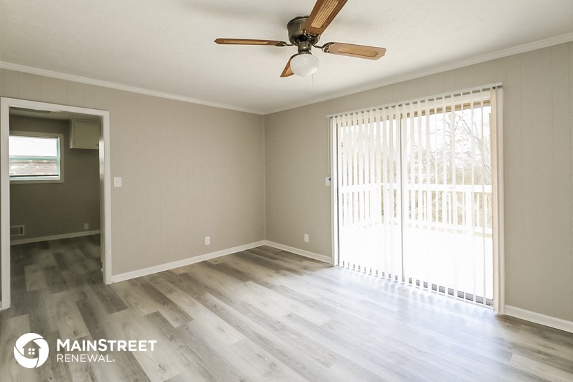 an empty living room with wood floors and a ceiling fan