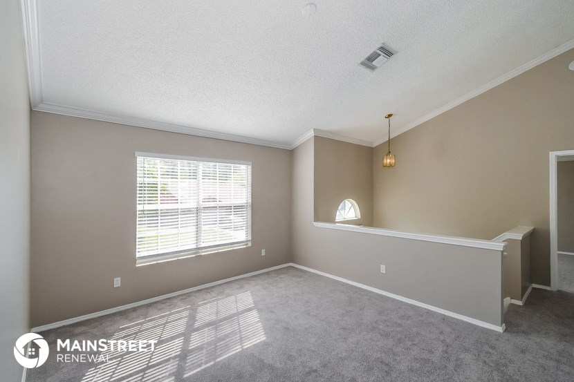 the spacious living room with a large window and carpet