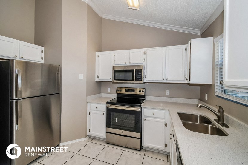 the kitchen has stainless steel appliances and white cabinets