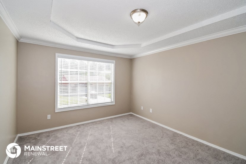 the spacious living room of a rental home with a large window
