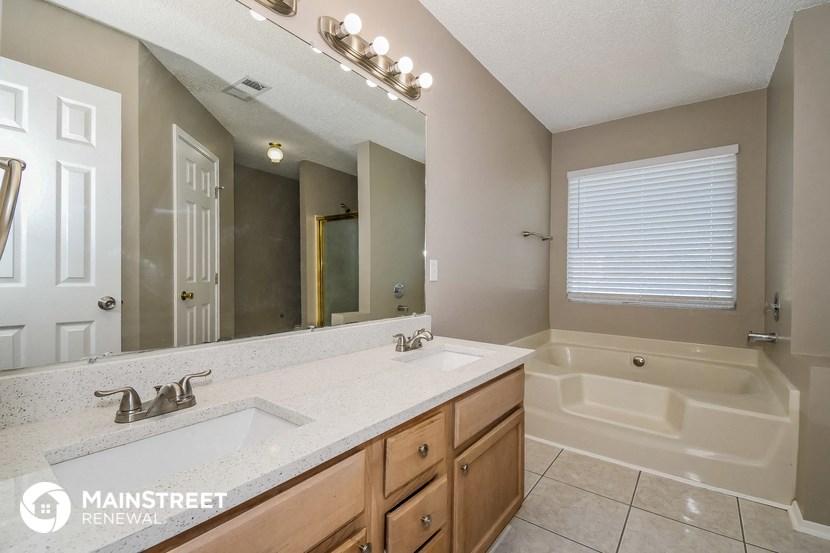 the master bathroom has a large mirror and a sink and a tub