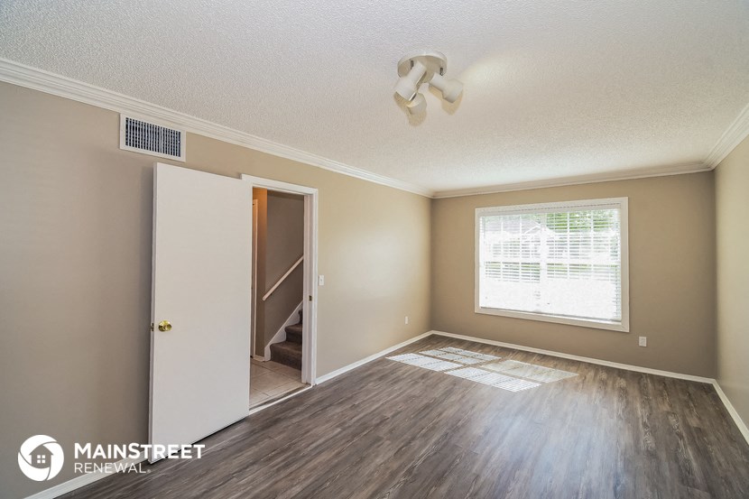 the living room of an apartment with wood flooring and a window