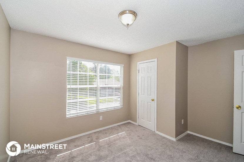 the spacious living room with a large window and carpeted flooring